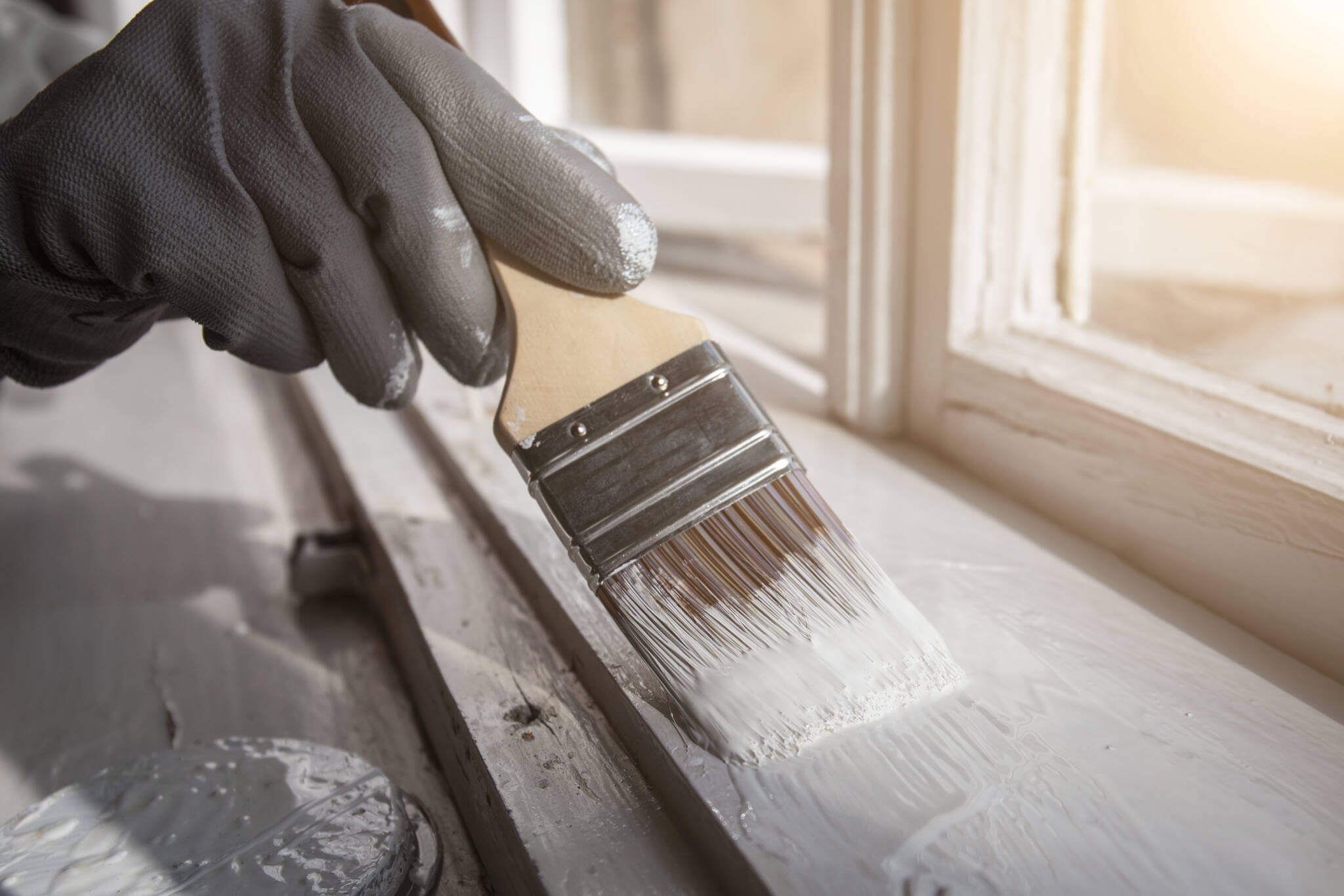 Painting Wooden Window With White Color. Brush In Hand With Grey Glove. Ronoveation And Restauration